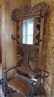 Full view of antique oak hall tree showing carved wooden details, beveled mirror, and metal coat hooks.