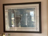 Frontal view of framed print showing bird artwork, wood frame, matting, and glass reflection
