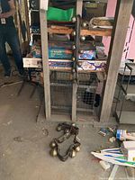 Three sets of brass bells on leather straps shown on basement floor and shelf.