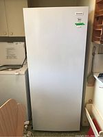 Exterior front view of white upright freezer closed