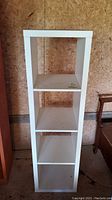 Front view of the white manufactured wood bookcase with 4 shelves, showing some dirt and minor scuffs.