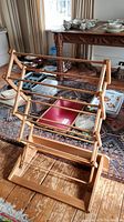 Wood foldable rack shown open on wood floor next to table with dishes and decorative items