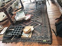 Full view of rug on wood floor under table with miscellaneous items on top