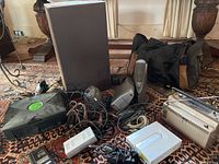 Overview of lot showing original Xbox console, speakers, power supplies, and miscellaneous cables and devices on carpet