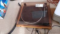 Full view of the turntable with woodgrain base and closed dust cover showing the overall condition and build of the unit.