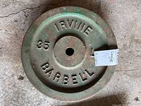 Close-up photo of one weight plate showing embossed text and weathered green paint with rust.