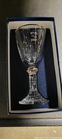 Crystal clear glass Kiddush cup with Hebrew engraving and gold accent displayed in a blue velvet-lined box.