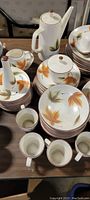 Full view of the ceramic vintage plate set displaying teapot, cups, salad plates, and dinner plates with fall leaves design in autumn colors