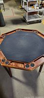 Octagonal poker table showing full playing surface, wooden border, and cup holders.