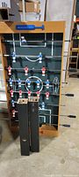Full view of the foosball table standing upright, showing wooden frame, metal rods, player figures in red and blue, and score counters.