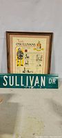 Framed O'Sullivan family history display with accompanying Sullivan Drive street sign placed in front.