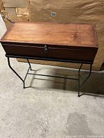 Full view of the small wood chest on the iron stand showing the top and structure.