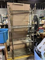 Photo of the full shelf showing its height, structure, and four glass shelves supported by brass frame