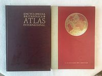 Photo showing front covers of the two vintage atlases side by side on a white surface.