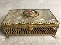 Front view of the antique decorative box showing mother-of-pearl lid with gold-tone metal trim and clasp, lattice base and feet.
