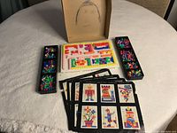 Full game set with pegboard, trays with pegs, and design cards arranged on a white table.