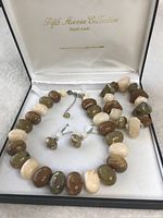 Photo showing the handmade beaded necklace, bracelet, and earrings set inside a white fabric-lined box with 'Fifth Avenue Collection Handmade' branding on the lid.