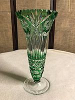 Full view of the vase standing upright showing the flared green crystal with detailed cut patterns and clear base.