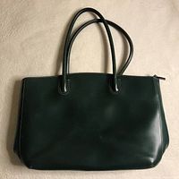 Front view of the forest green leather purse showing smooth surface and two handles.