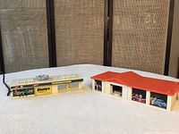 Mattel Sizzlers Charging Station on left, Power Pit garage on right, both on white surface with woven screen background