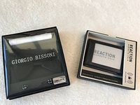 Packaged Giorgio Bissoni black silk bowtie with cufflinks and white kerchief along with Reaction Kenneth Cole RFID-blocking wallet in box.