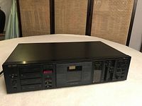 Front view of the Nakamichi BX-300 cassette deck showing cassette compartment, digital counter, control sliders, and buttons.