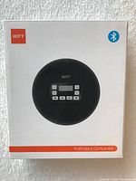 Front of the box showing branding, Bluetooth symbol, and image of the black portable CD player with display and control buttons.