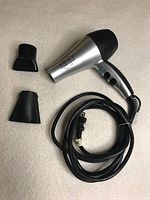 Rusk Hyper Ionic blow dryer laid out with two attachments and power cord coiled beside it on a light-colored surface.