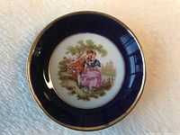 Top-down view showing detailed painted romantic couple scene in center and cobalt blue border with gold rim