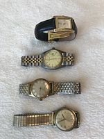 Front view of four watches on white surface showing faces and bands