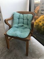 Solid wood vintage 1960s armchair with curved armrests and a tufted light turquoise seat and back cushion placed on balcony