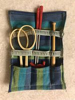 Plaid fabric roll-up bag holding miniature sports equipment including two tennis rackets, a baseball bat, two golf clubs, and other small accessories.