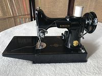 Side view of black enamel Singer sewing machine on its base