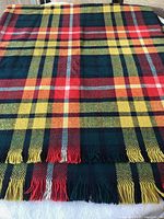 Front view of wool blanket spread flat with plaid pattern and fringed ends.