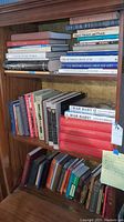 Three-shelf wooden bookcase loaded with assorted firearms history books
