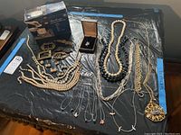 Overview of lot on table showing cleaner kit, belt buckles, necklaces, earrings, ring