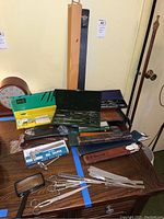 Table layout showing dial calipers, slide rules, leather cases, drafting tools and magnifier