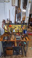 Full view of assorted hand tools on workbench with saws hanging and tools laid out in front
