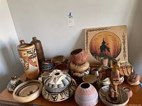 Overall view of collection on table showing tall ceramic vase, bottles, pots, bowls and painting