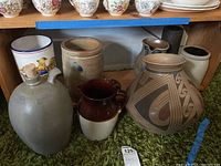Wide angle showing the collection of pottery including jugs, crocks, and decorative base vase.