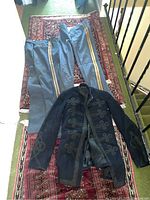 Photo of replica Civil War military uniform pants and jacket laid on patterned rug along stairwell