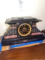 Top angled view displaying curved roof, black finish, floral accents and winding key on top