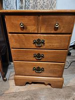 Front view of Ethan Allen commode style table showing wood finish and drawer hardware