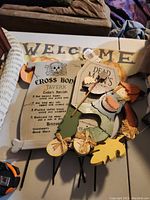 Wooden welcome sign and Halloween decor items including Cross Bones Tavern menu and a pumpkin decoration with autumn leaves.