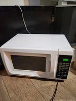 White Walmart EM720CGA-W microwave oven with digital control panel and green LED display