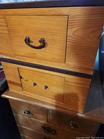 Close-up of upper part of wooden drawer unit showing large drawer with curved metal handle.