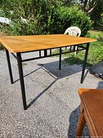 Full view of the vintage solid wood table showing the wooden top and black metal legs with accents.