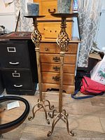 Pair of vintage metal plant stands side by side on wood floor with furniture background
