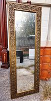 Front view of large full size rectangular mirror with an ornate carved solid wood frame in gold tone.