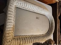 Front view of the vintage wicker framed mirror showing the entire mirror surface and surrounding wicker frame.